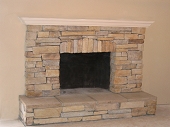 Eldorado stacked stone veneer fireplace with raised stone hearth and wood mantle