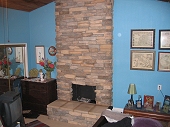 Floor to ceiling Eldorado stone veneer fireplace with raised stone hearth