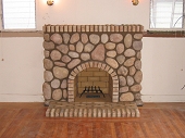 Eldorado river stone veneer fireplace with brick arch, firebox, hearth and mantle